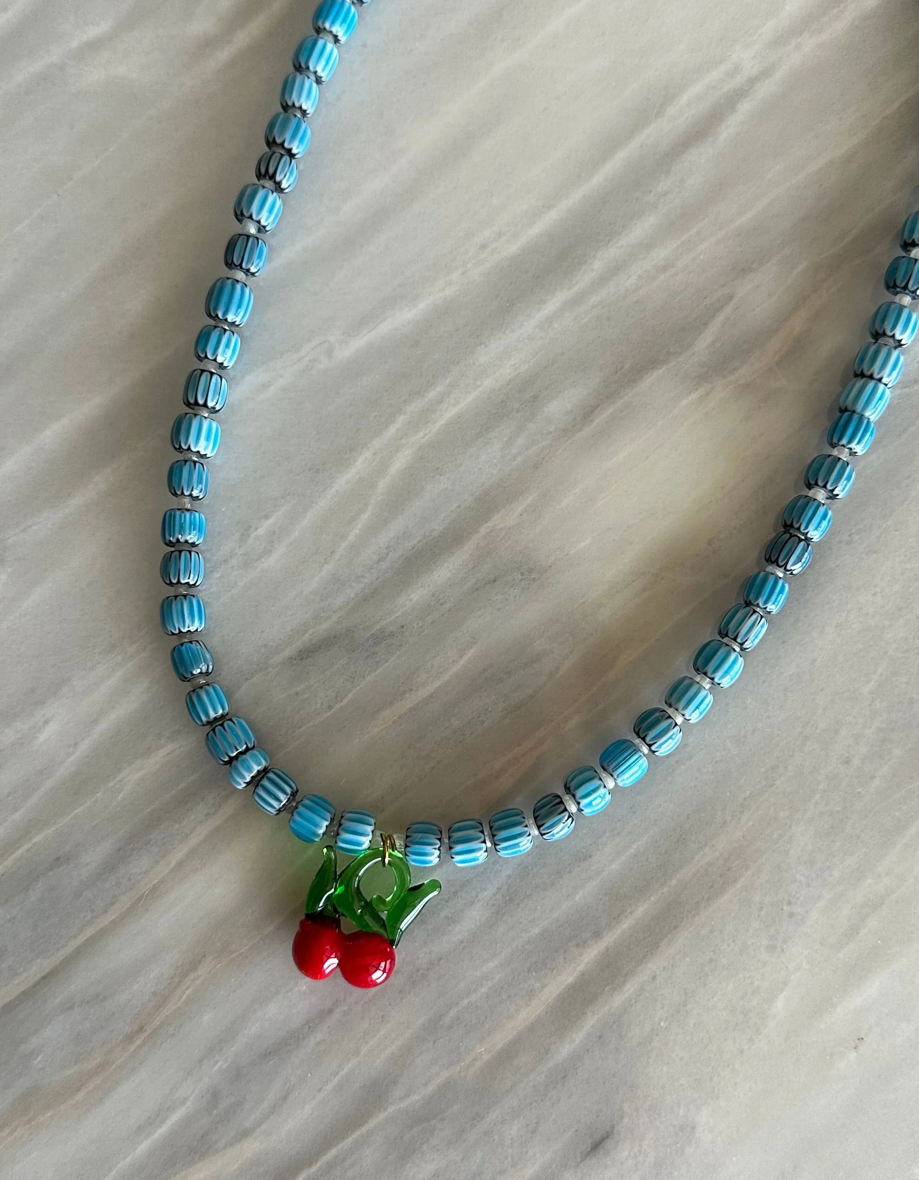 Collar con cerámica azul clarito, bolitas blancas y cerezas de cristal