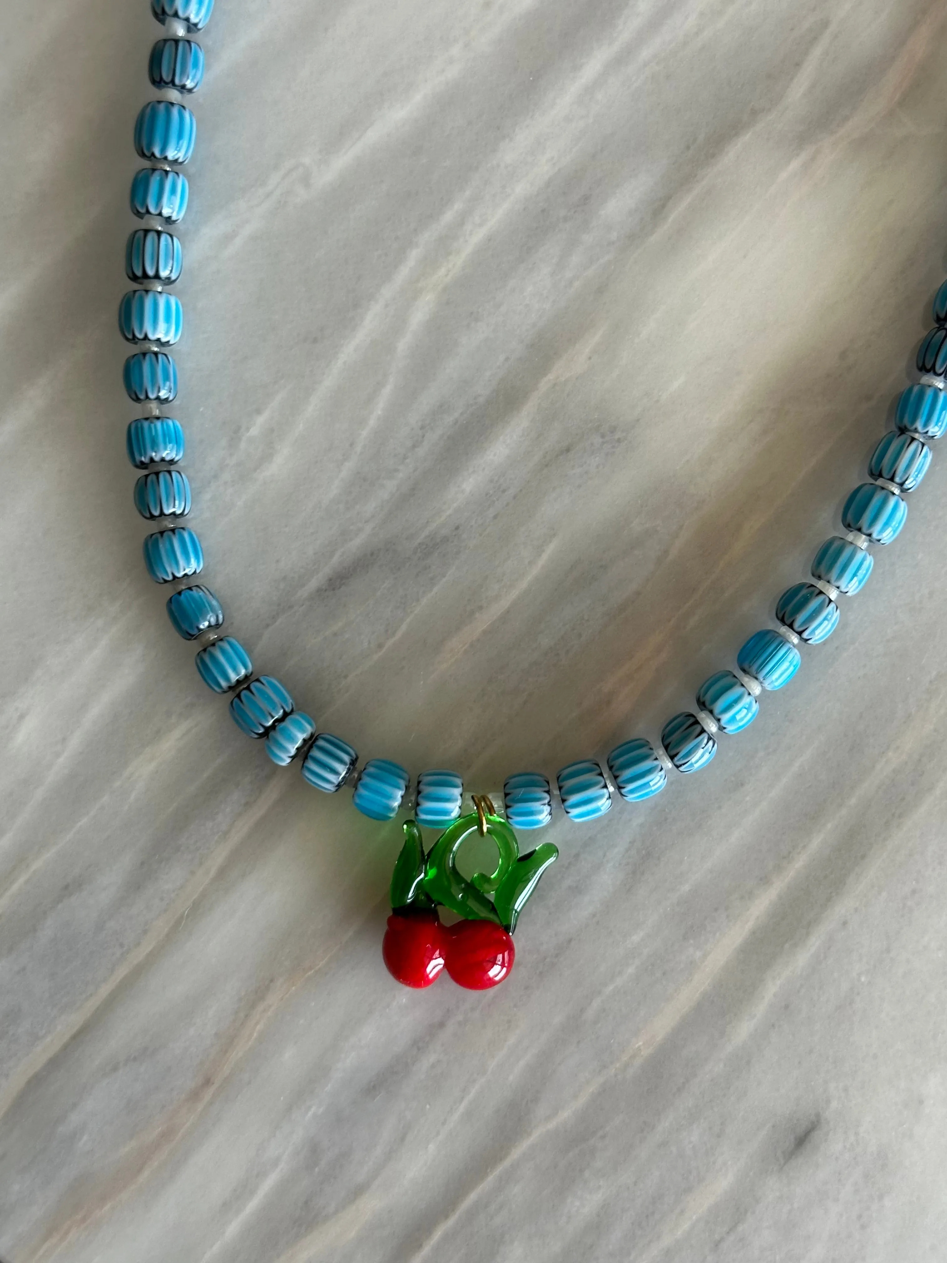 Collar con cerámica azul clarito, bolitas blancas y cerezas de cristal